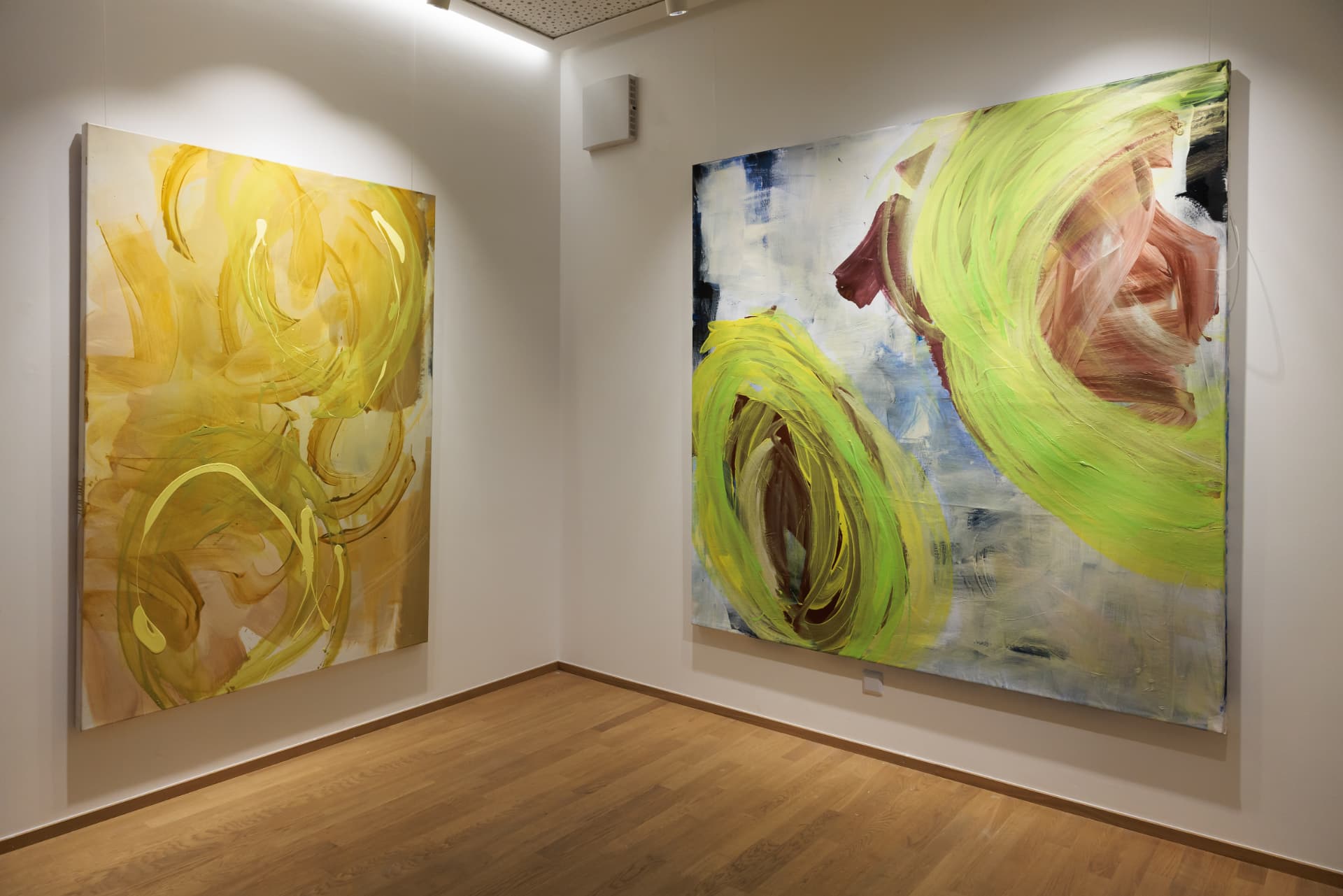 Two large yellow and green paintings on adjacent gallery walls